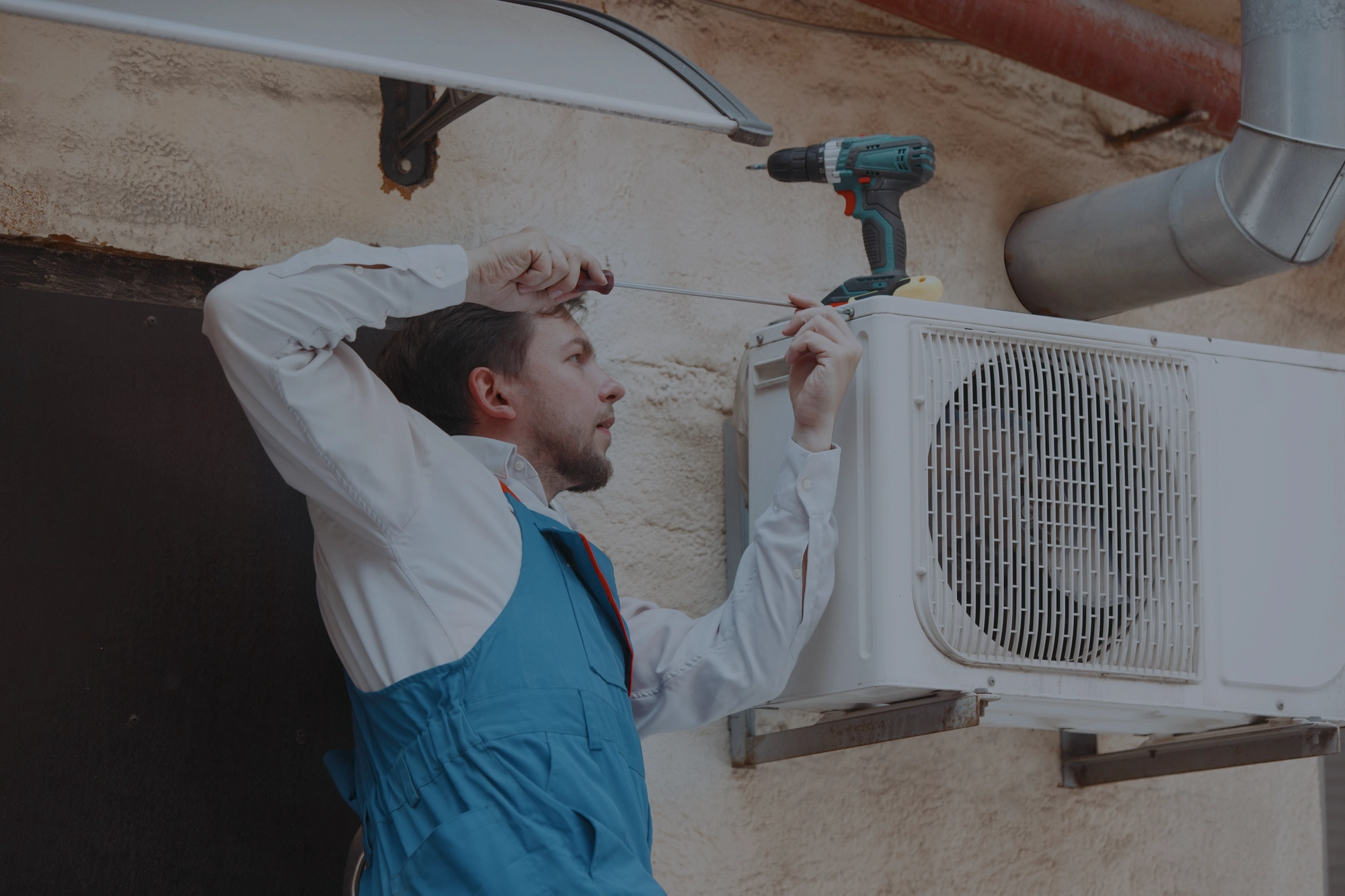 Technician performing a repair on an outdoor air conditioning unit with tools, ensuring effective cooling services in Greater Boston, MA.