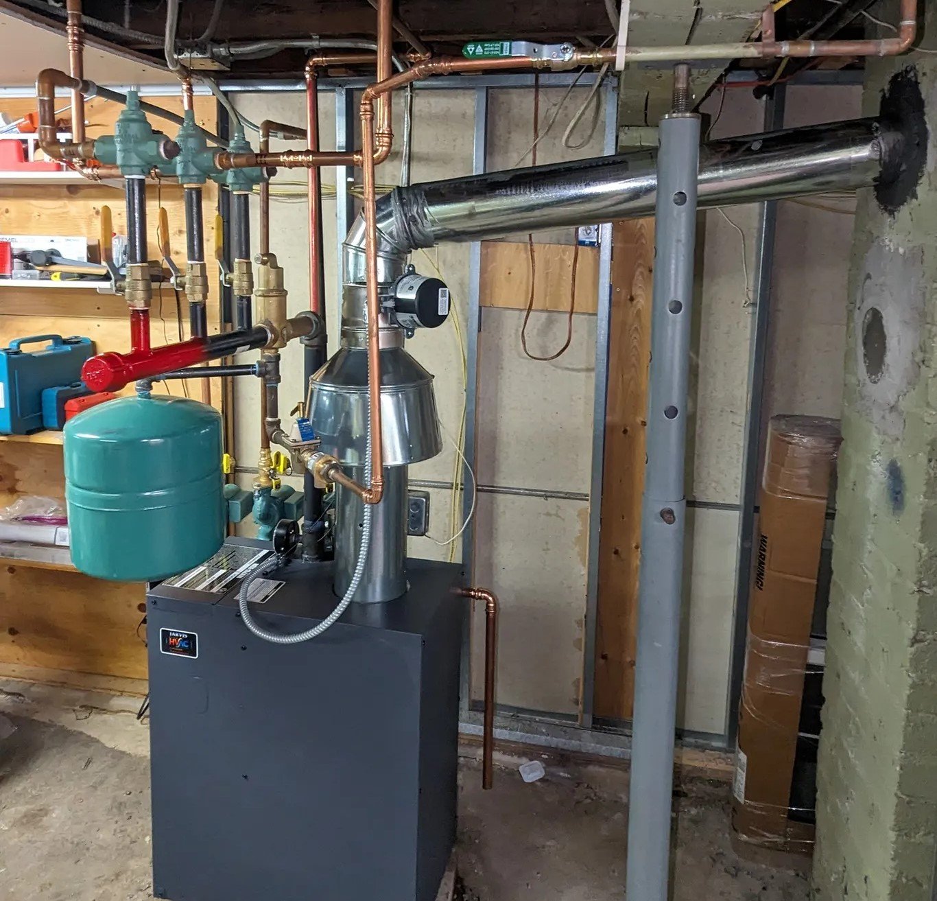 A well-maintained boiler system in a basement, featuring a green expansion tank and copper piping, highlighting professional heating system maintenance services in Boston, MA.